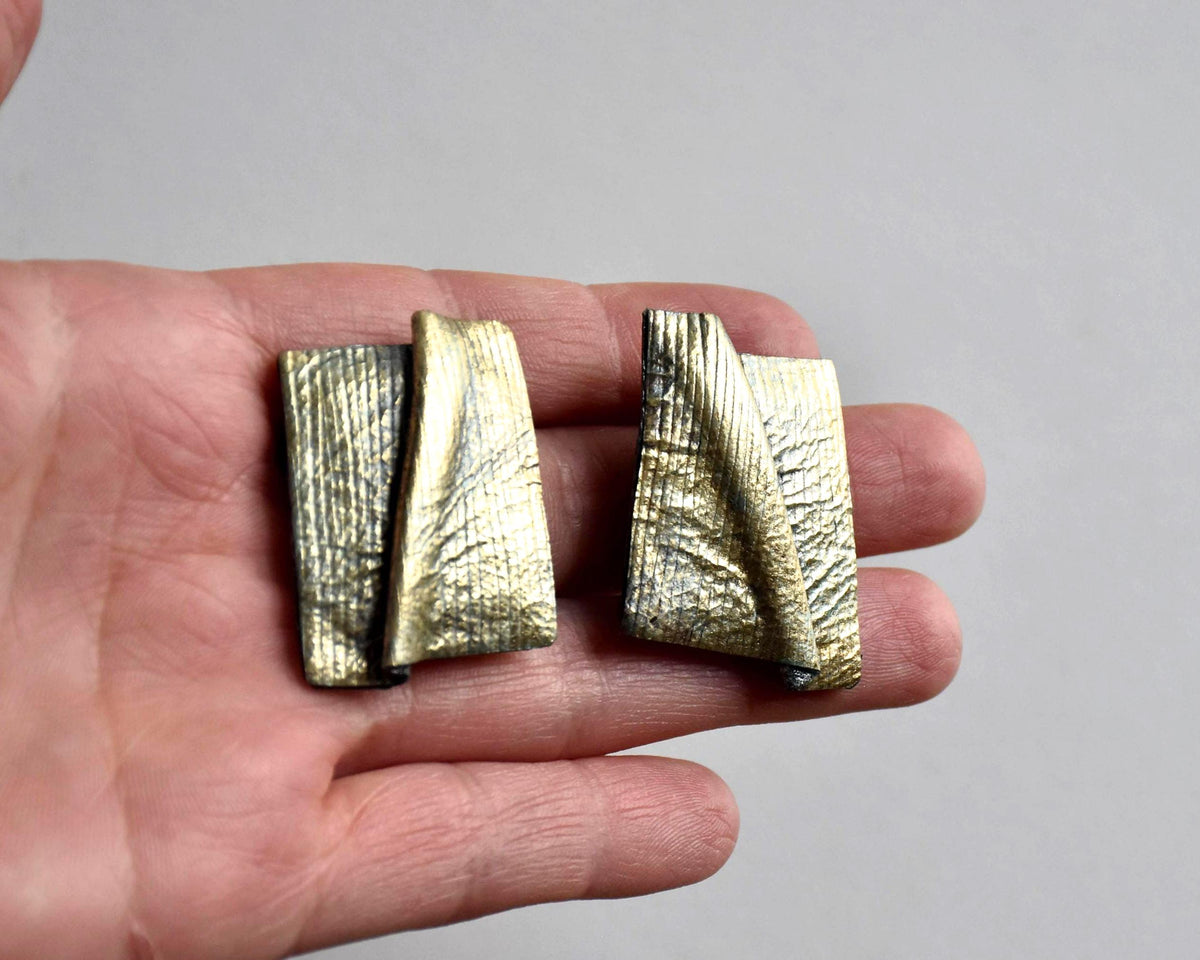 Matching clip-on earrings from the sculptural leather set shown from another angle in hand