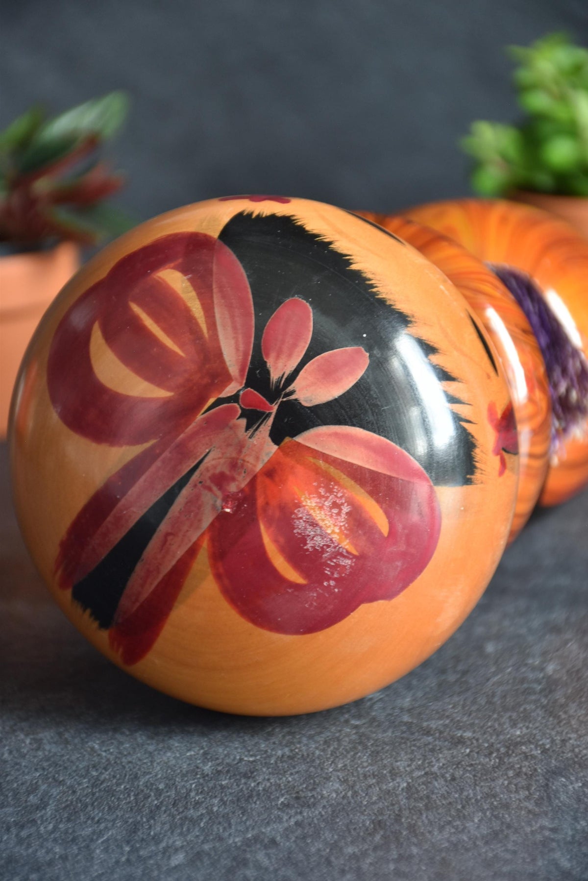 Sosaku kokeshi doll top view displaying the red floral motif on the wide rounded head
