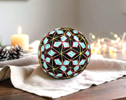 Hand-Embroidered Japanese Temari Ball Folk Art table scatter displayed on a linen cloth with a candle and pinecones