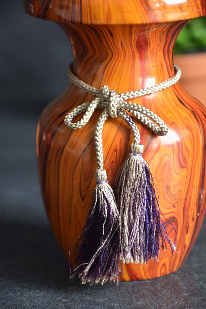 Sosaku kokeshi doll detail of the decorative braided cord and dual tassels