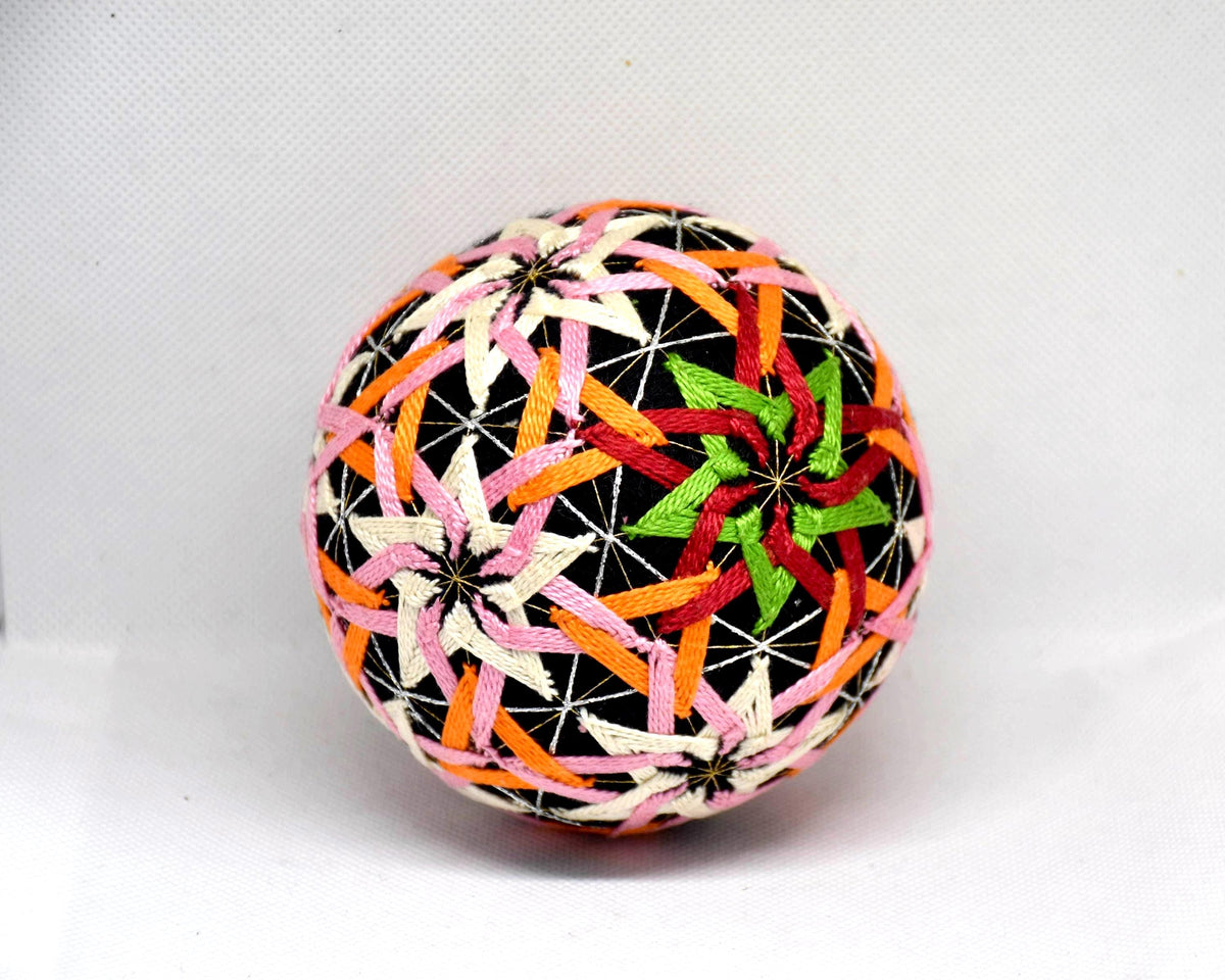 Temari ball hand embroidery featuring a detailed star-shaped motif in green, red, and orange