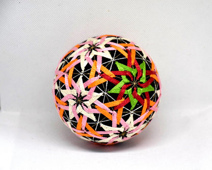 Temari ball hand embroidery featuring a detailed star-shaped motif in green, red, and orange