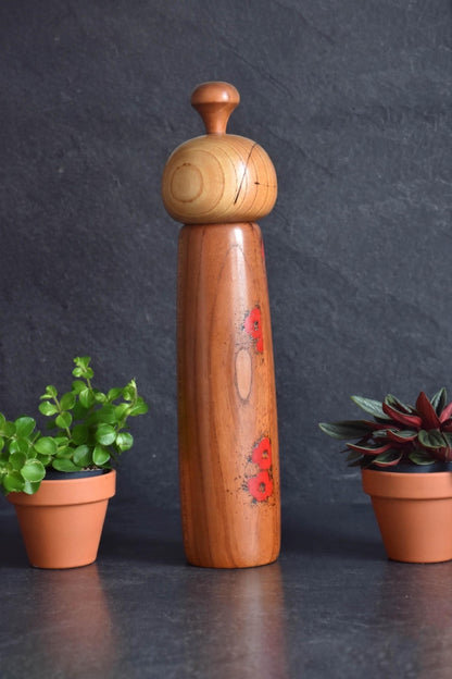 Toa Sekiguchi kokeshi doll shown upright with red floral motifs along the side