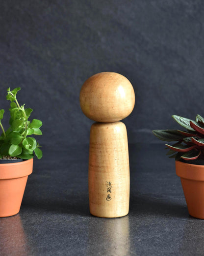 Kenichi Murakami kokeshi doll featuring the back view of the wooden carving
