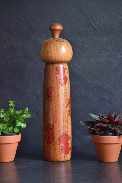 Toa Sekiguchi kokeshi doll standing alone featuring vibrant red camellia blossoms