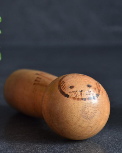 Kenichi Murakami kokeshi doll lying horizontally to show the round face and features