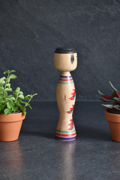 Kinichiro Sasaki kokeshi doll, angled side view highlighting the floral artwork and colorful bands