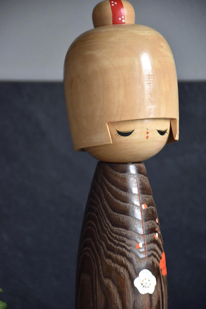 Usaburo kokeshi doll close-up on the head with closed eyes and red hair ornament