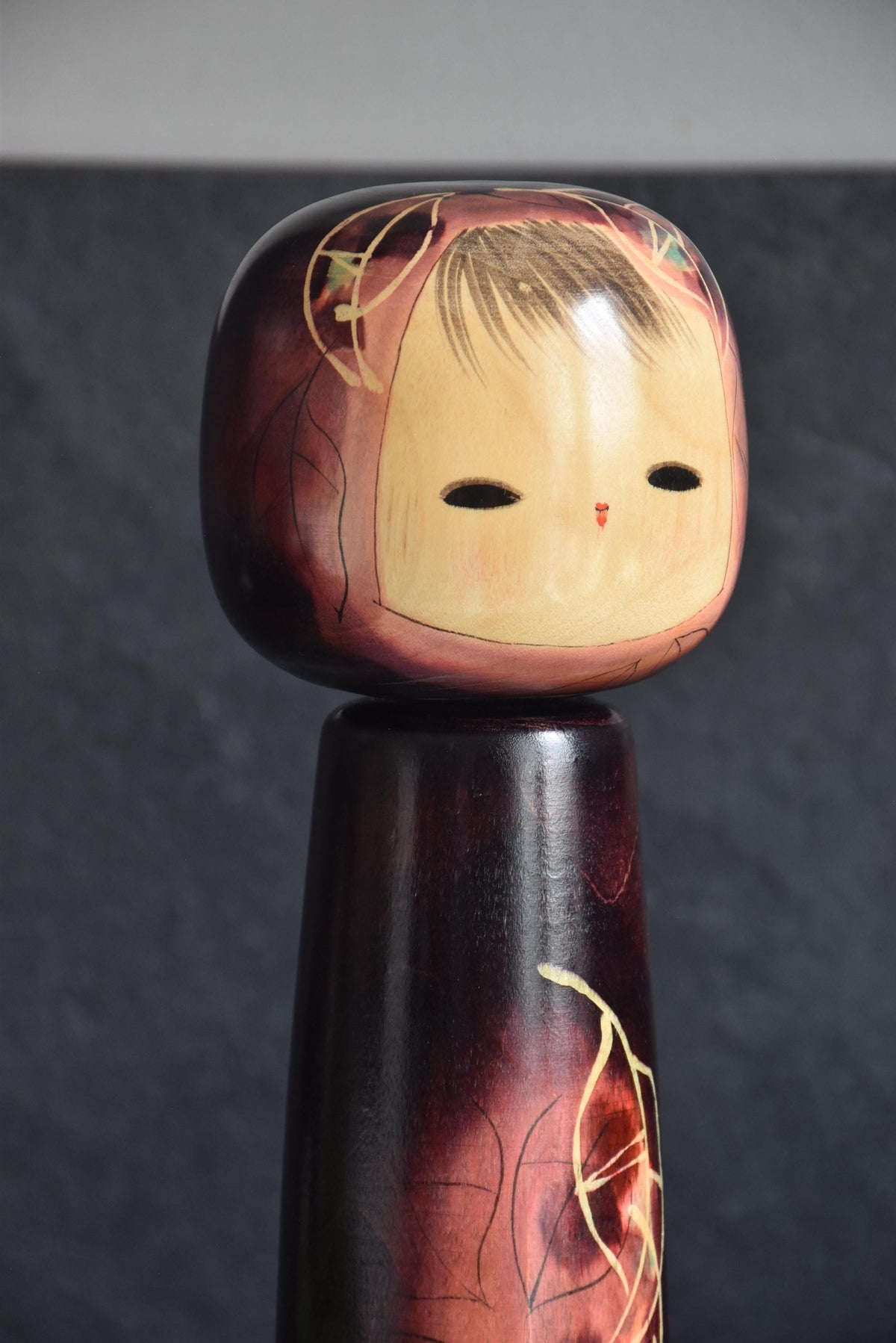 Masami Kato kokeshi doll close up of the painted face with wispy bangs and narrow eyes