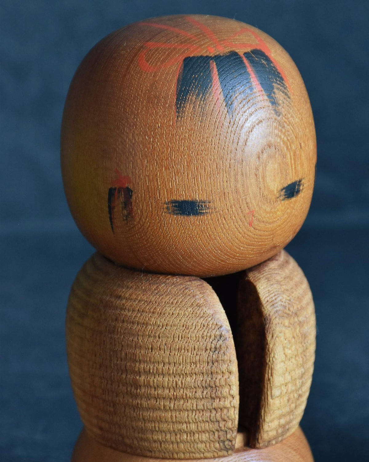 Aida Seihou kokeshi doll front closeup focusing on the hand painted face and topknot