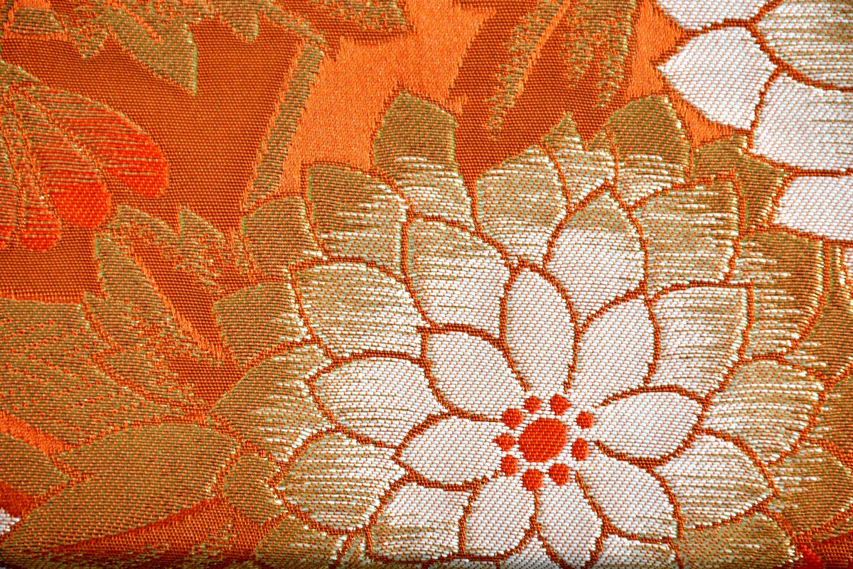 Saga Nishiki brocade clutch handbag close-up of the geometric and floral textile weave in orange and gold.