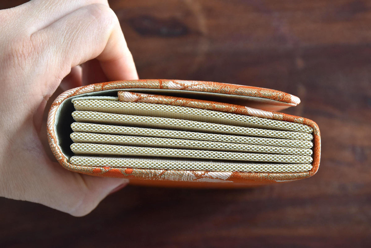 Saga Nishiki brocade clutch handbag side view displaying the structured accordion style folds and beige fabric gussets.