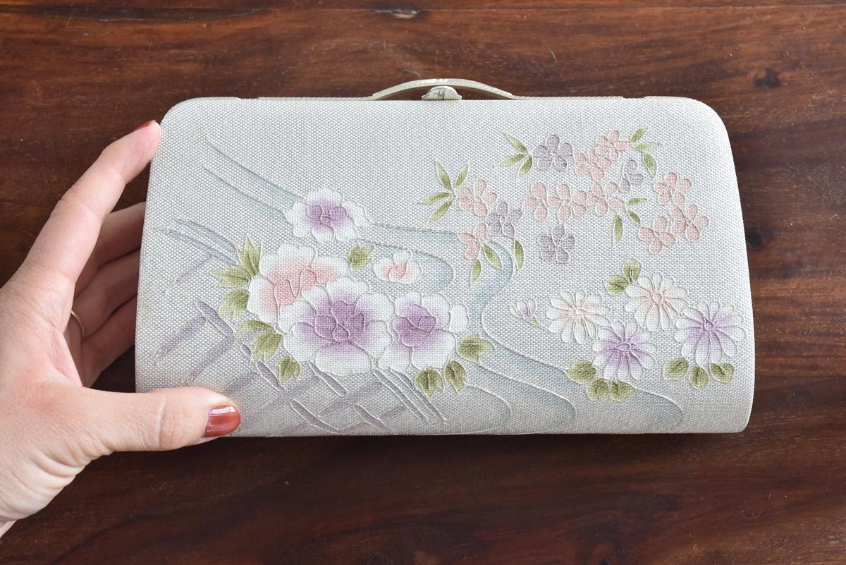 Japanese Floral Clutch With Raised Metallic Cord Detail shown next to a hand for scale
