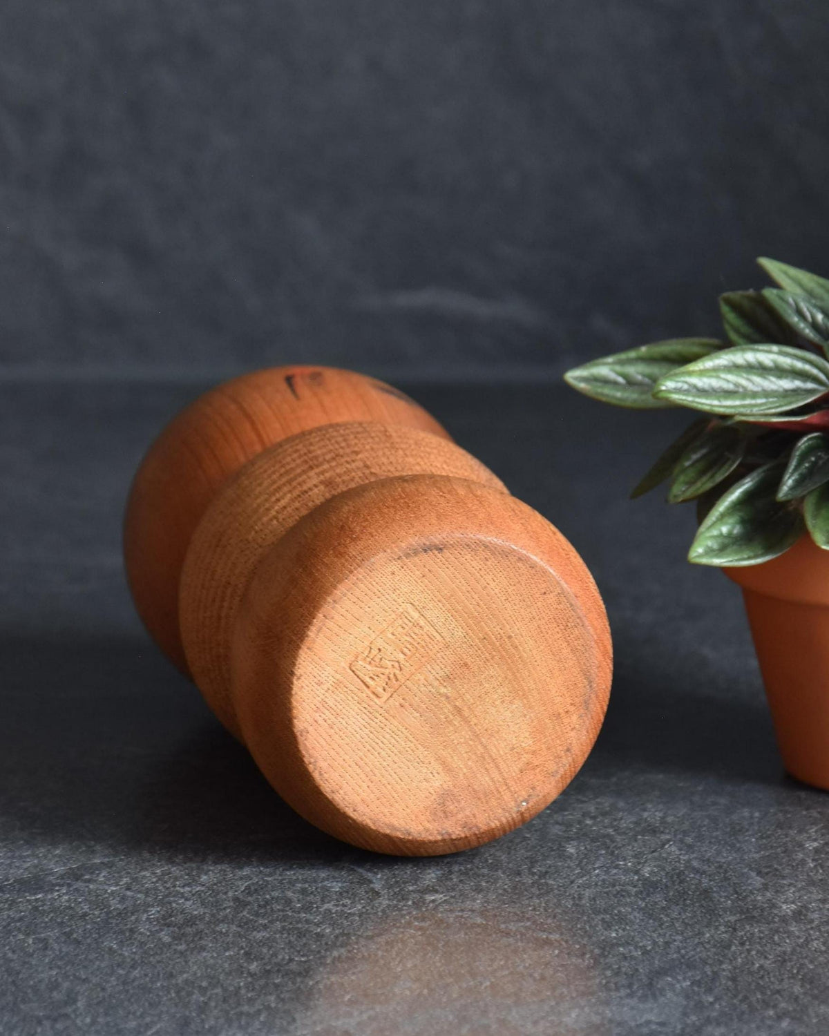 Aida Seihou kokeshi doll angled to show the flat bottom base with maker mark signature
