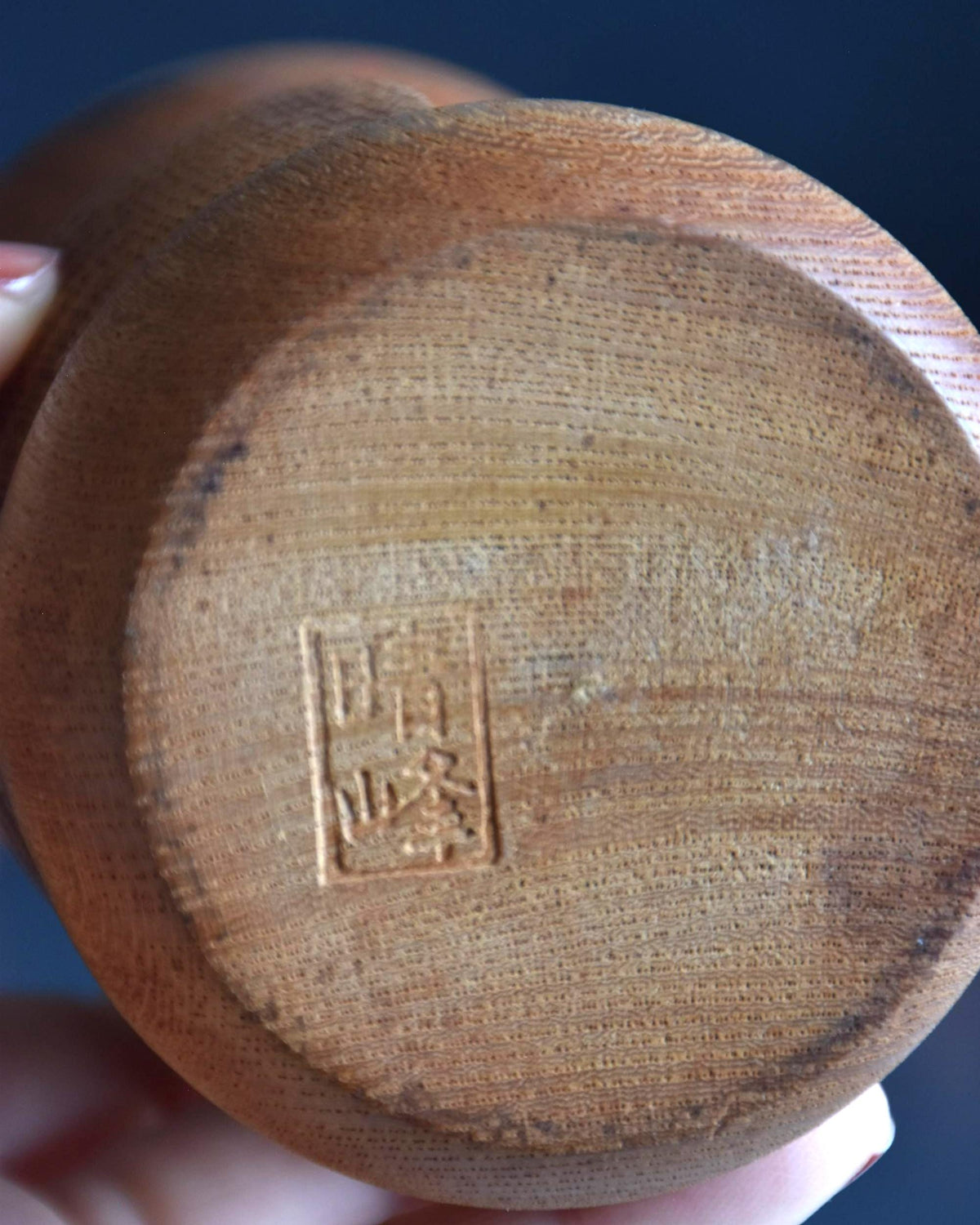 Aida Seihou kokeshi doll bottom base closeup showing the stamped artisan signature stamp