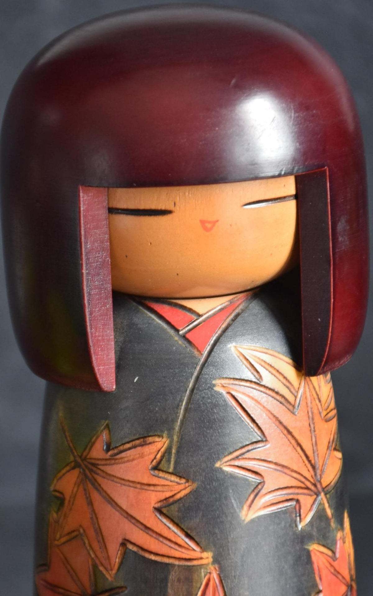 Kohji Sumiya kokeshi doll closeup of serene facial expression and red collar
