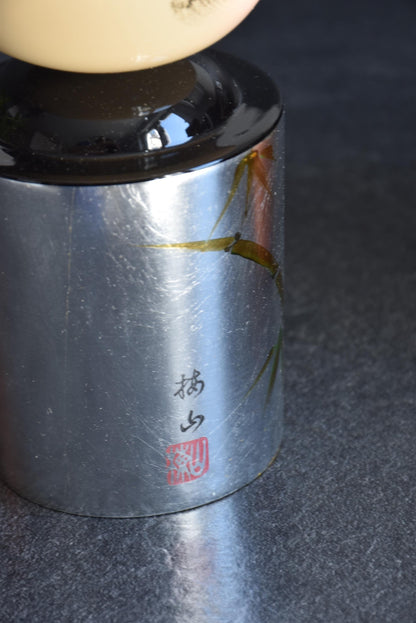 Hanawarabe kokeshi doll body detail showing the painted signature and red stamp