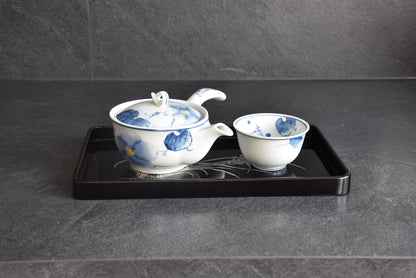 Black lacquer serving tray styled with a decorative blue and white ceramic teapot and teacup