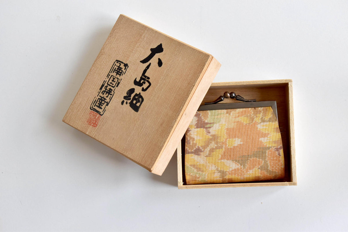 Oshima Tsumugi Silk Gamaguchi Coin Purse placed inside its wooden box viewed from an angled top perspective