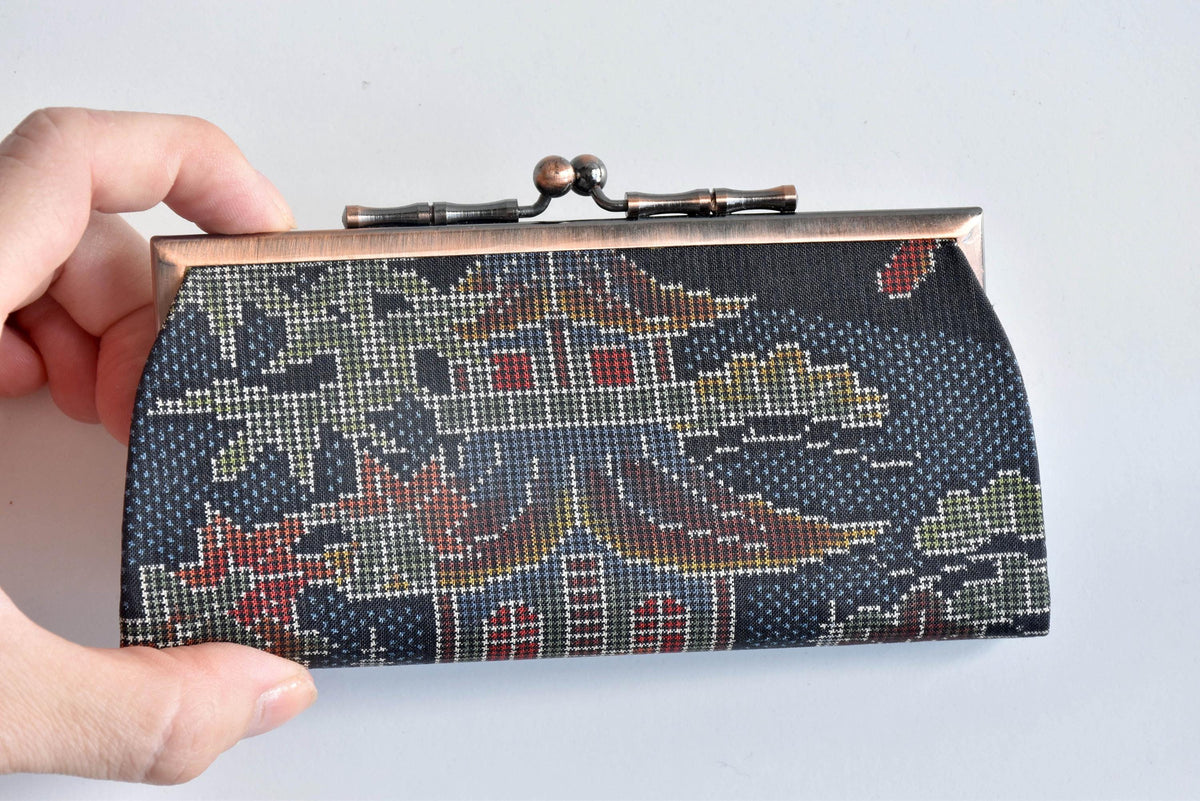 Blue Oshima Tsumugi Silk Gamaguchi Coin Purse held next to a hand to demonstrate its compact size and proportions