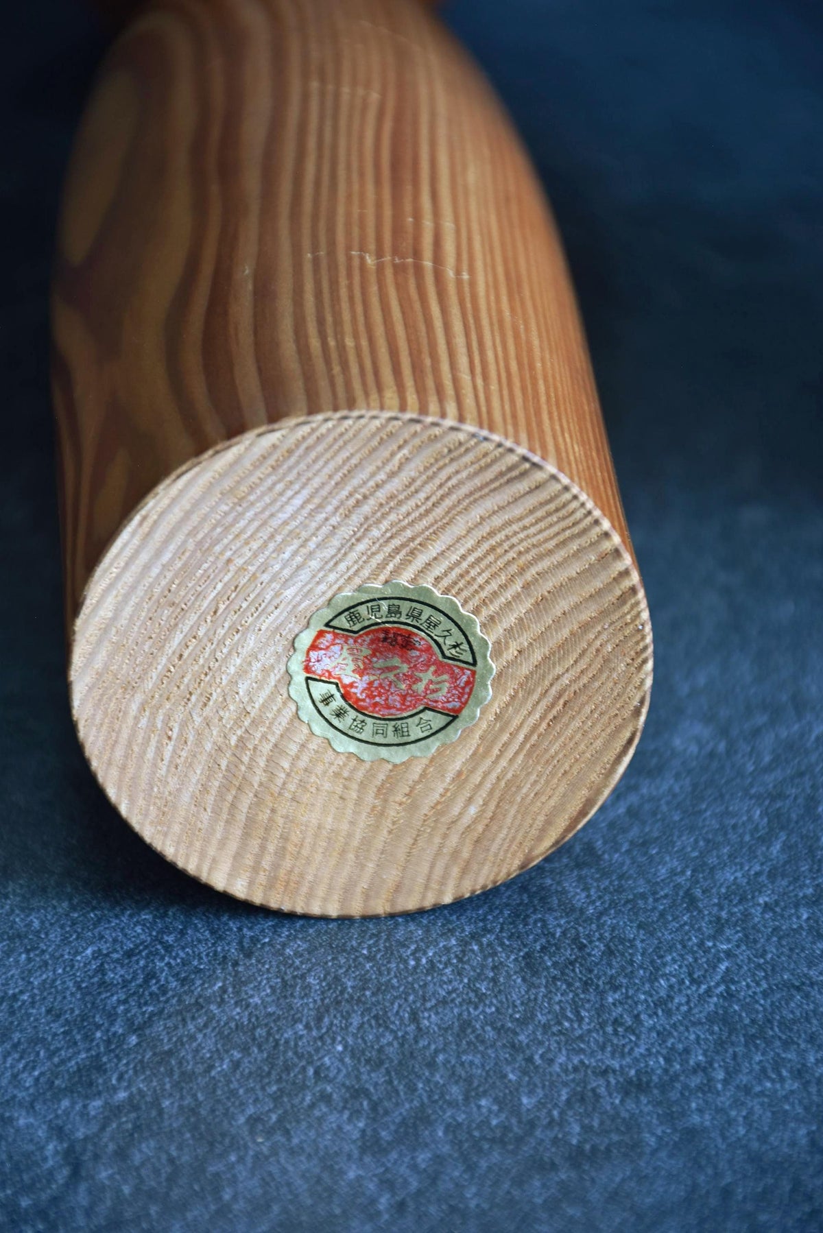 Sosaku Kokeshi doll in Yakusugi cedar wood showing the base with authenticity sticker