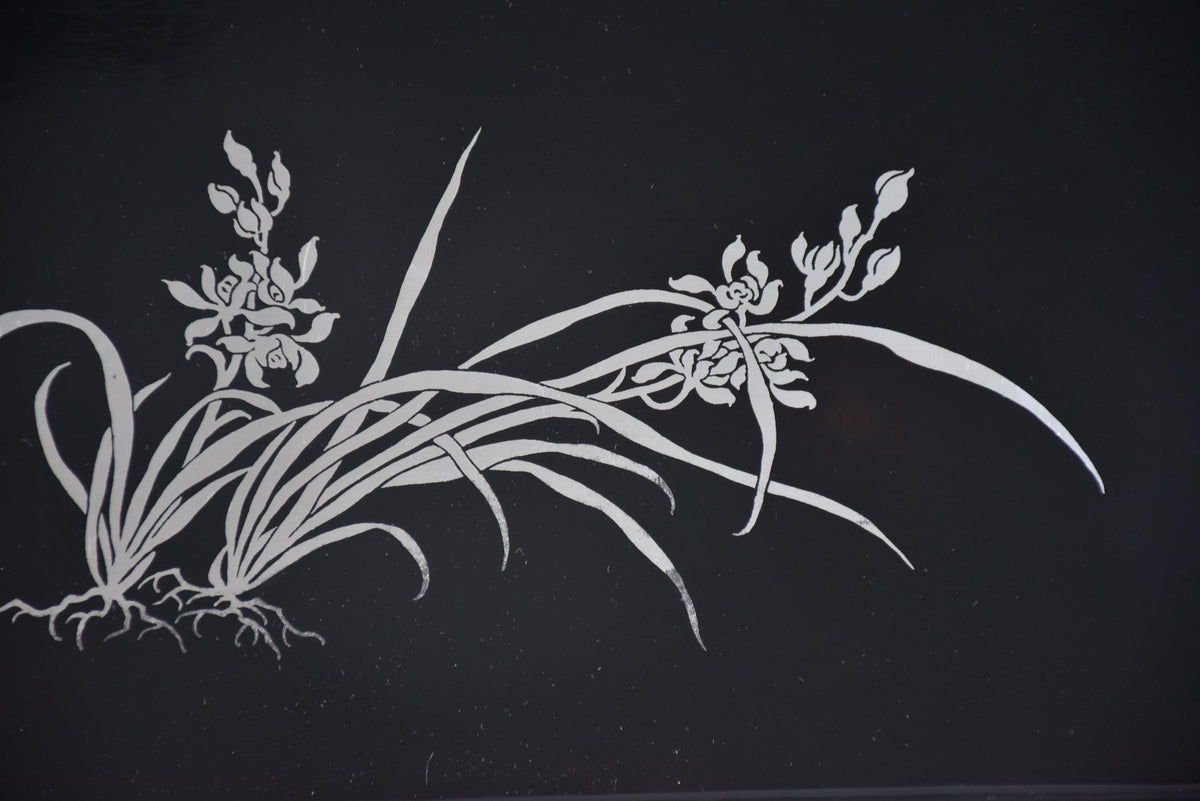 Close-up angle highlighting the detailed silver orchid flower and root pattern on the tray