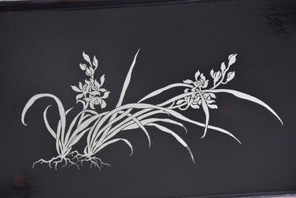 Close-up of the silver orchid inlay design featuring flowing leaves and roots on the tray