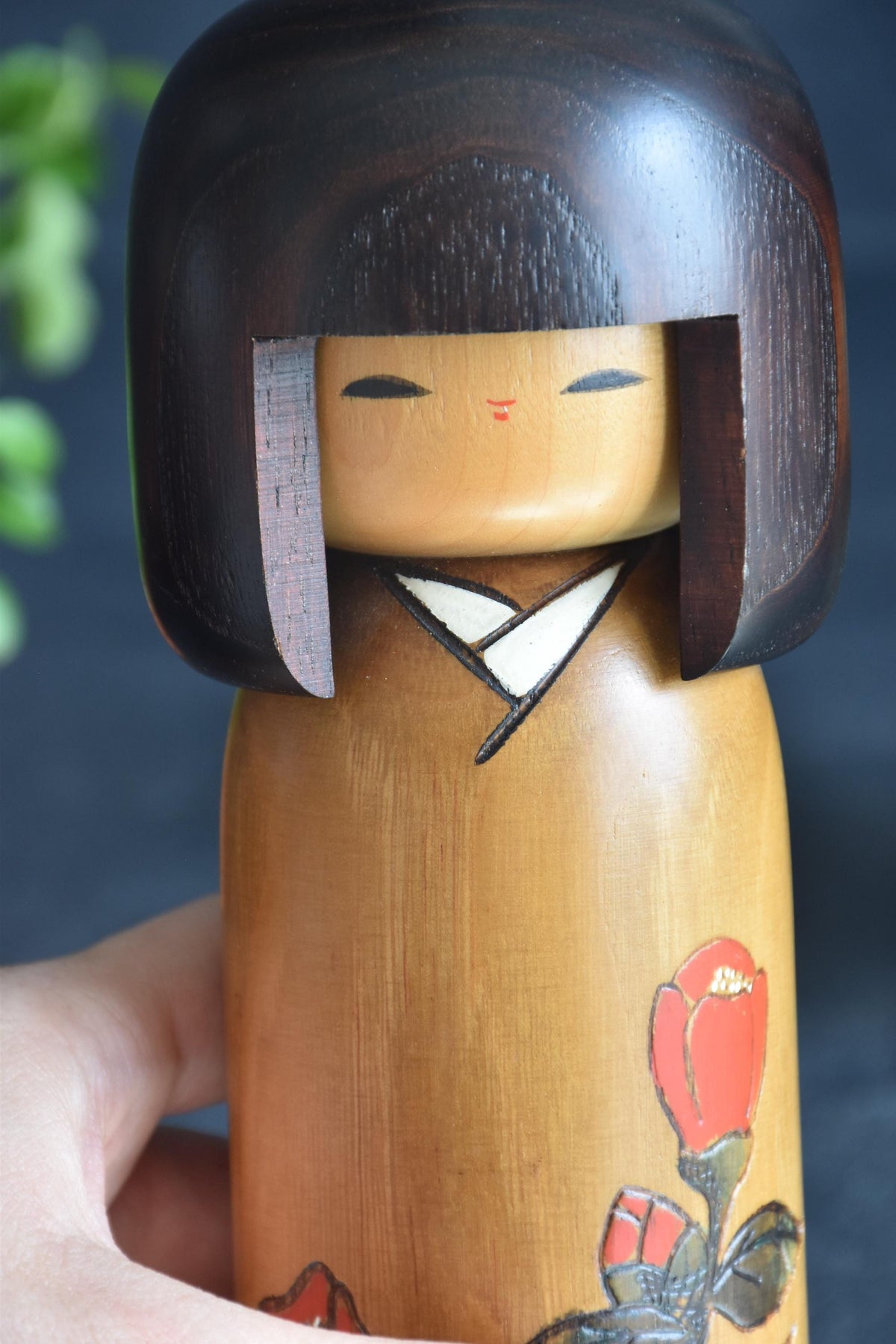 Usaburo Sosaku Kokeshi Tsubakikoyomi Camellia Doll held next to a hand for scale