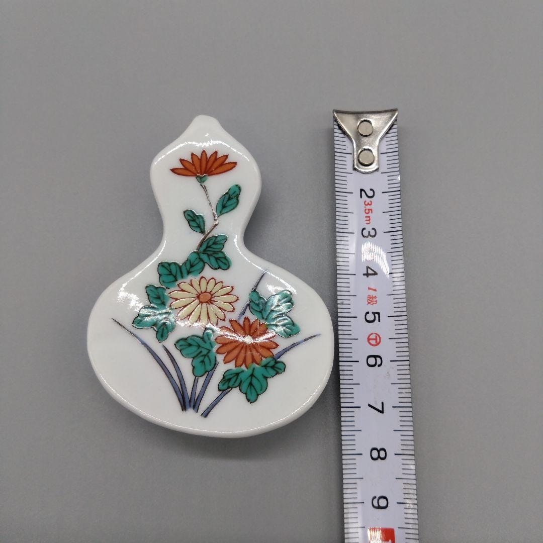 Floral Gourd Porcelain Chopstick Rest measured vertically alongside a tape measure