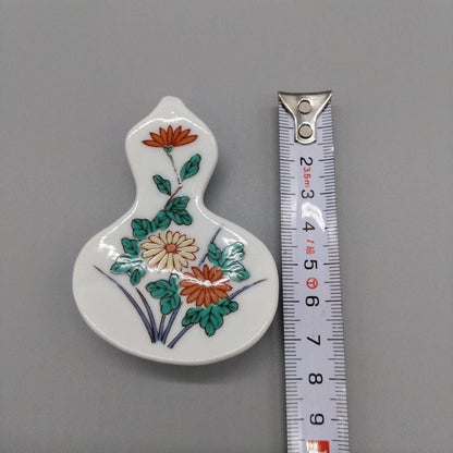Floral Gourd Porcelain Chopstick Rest measured vertically alongside a tape measure