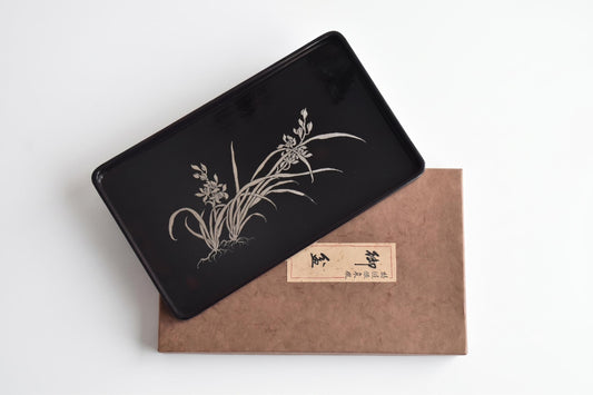 Black Lacquer Serving Tray With Silver Orchid Inlay displayed diagonally over its original storage box