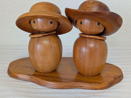 Yakusugi Cedar Sosaku Kokeshi Dolls With Sun Hats standing together on a matching wood display base