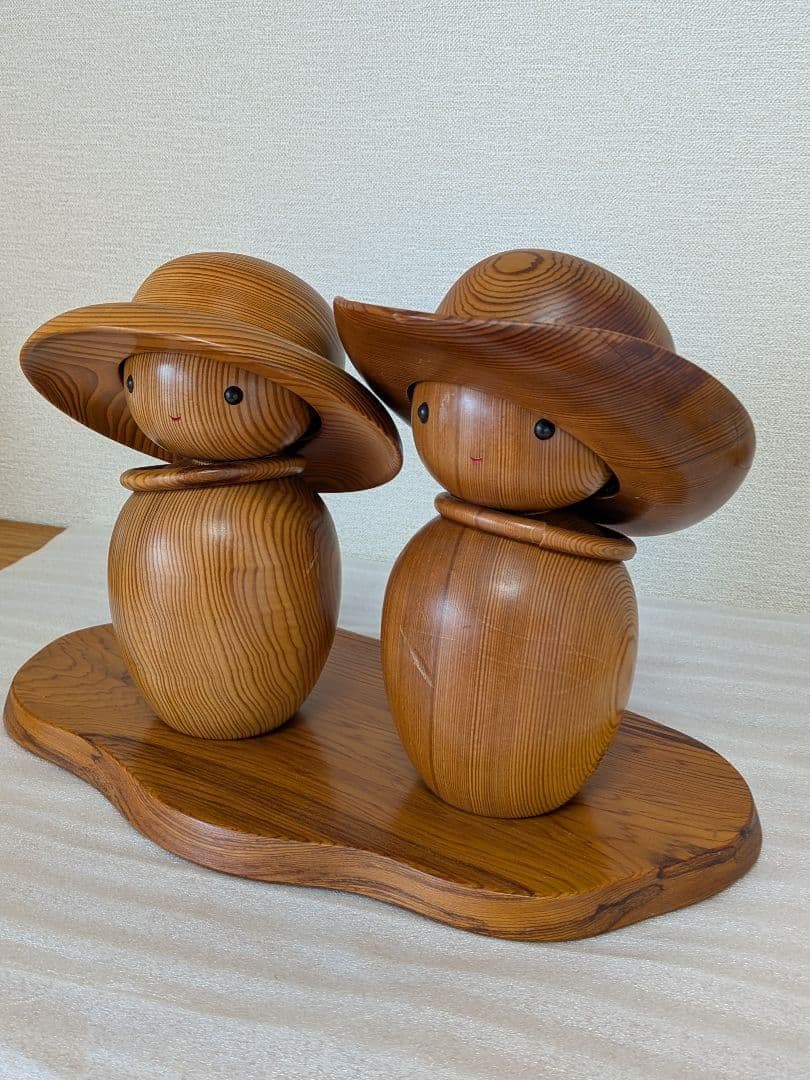 Yakusugi Cedar Sosaku Kokeshi Dolls angled view displaying the rich wood grain and tilted sun hats