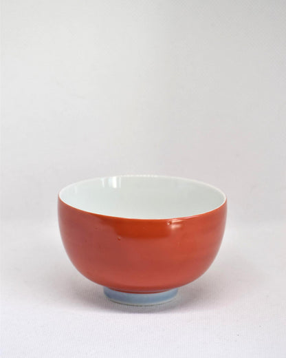 Koransha tea cup set featuring a single red porcelain bowl held next to a hand for scale