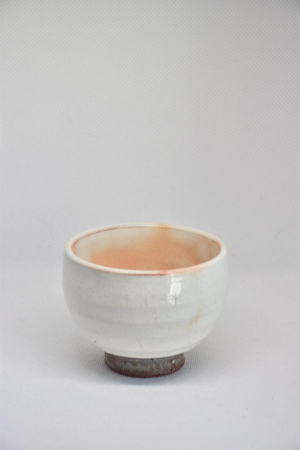 Set Of 5 White Kumidashi Teacups single cup front profile resting on its unglazed dark clay base foot