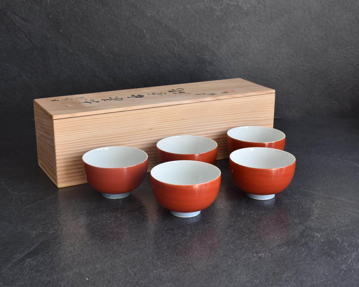 Koransha tea cup set featuring five red bowls displayed in front of the tomobako storage box