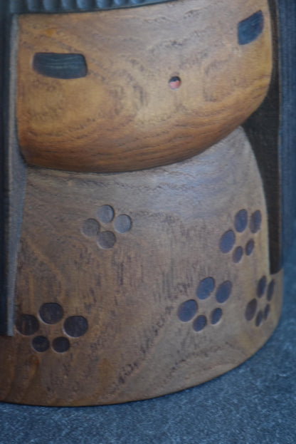 Sanpei Yamanaka kokeshi kimono detail showing burnished flower motifs on warm wood