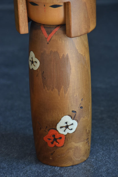 Usaburo kokeshi doll pattern detail showing the painted and wood-burned plum blossoms