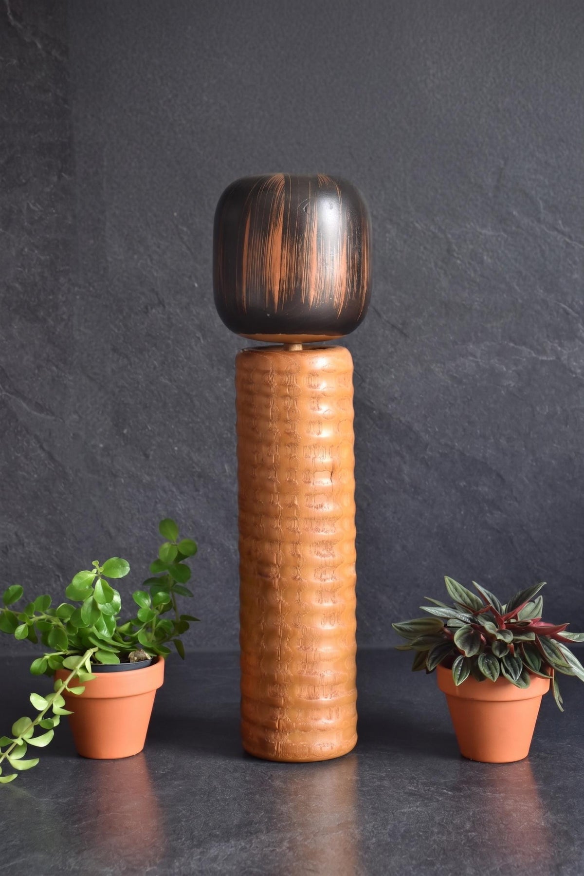 Usaburo Sosaku Kokeshi doll side profile showing the cylindrical shape and wood grain texture
