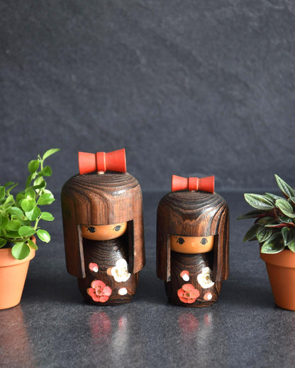Sosaku Kokeshi Pair With Red Ribbons And Floral Motifs made from dark wood