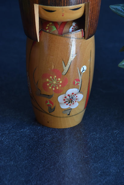 Kojo Tanaka Sosaku Kokeshi doll front view showcasing the painted ume flower body
