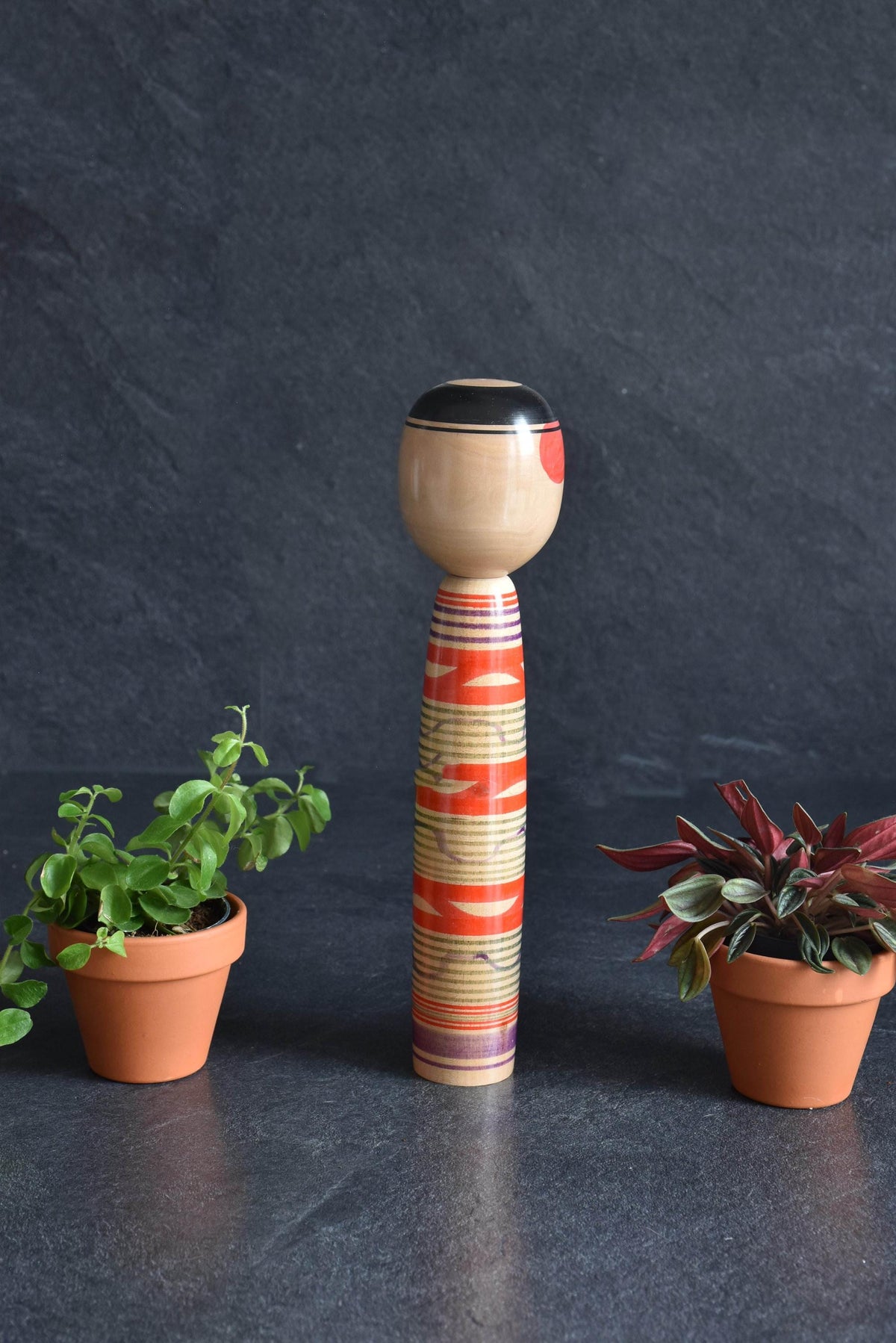 Tsuchiyu kokeshi doll showcasing a side profile of the hand-painted face and body patterns