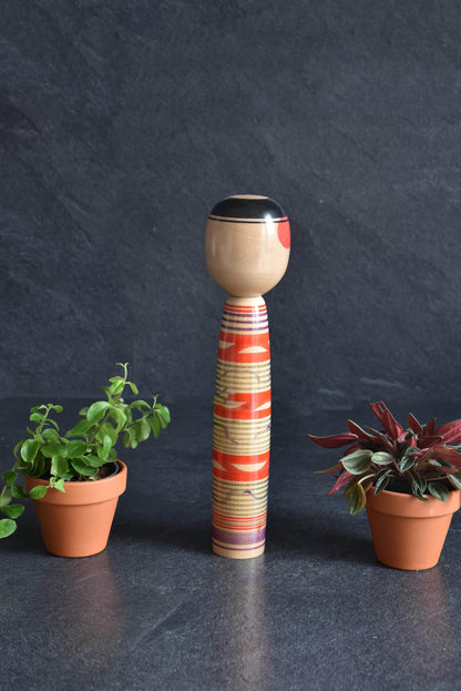 Tsuchiyu kokeshi doll showcasing a side profile of the hand-painted face and body patterns