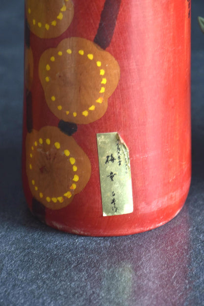 Hakuho Sosaku Kokeshi doll gold maker label closeup showing Japanese handwritten characters on the gold sticker.
