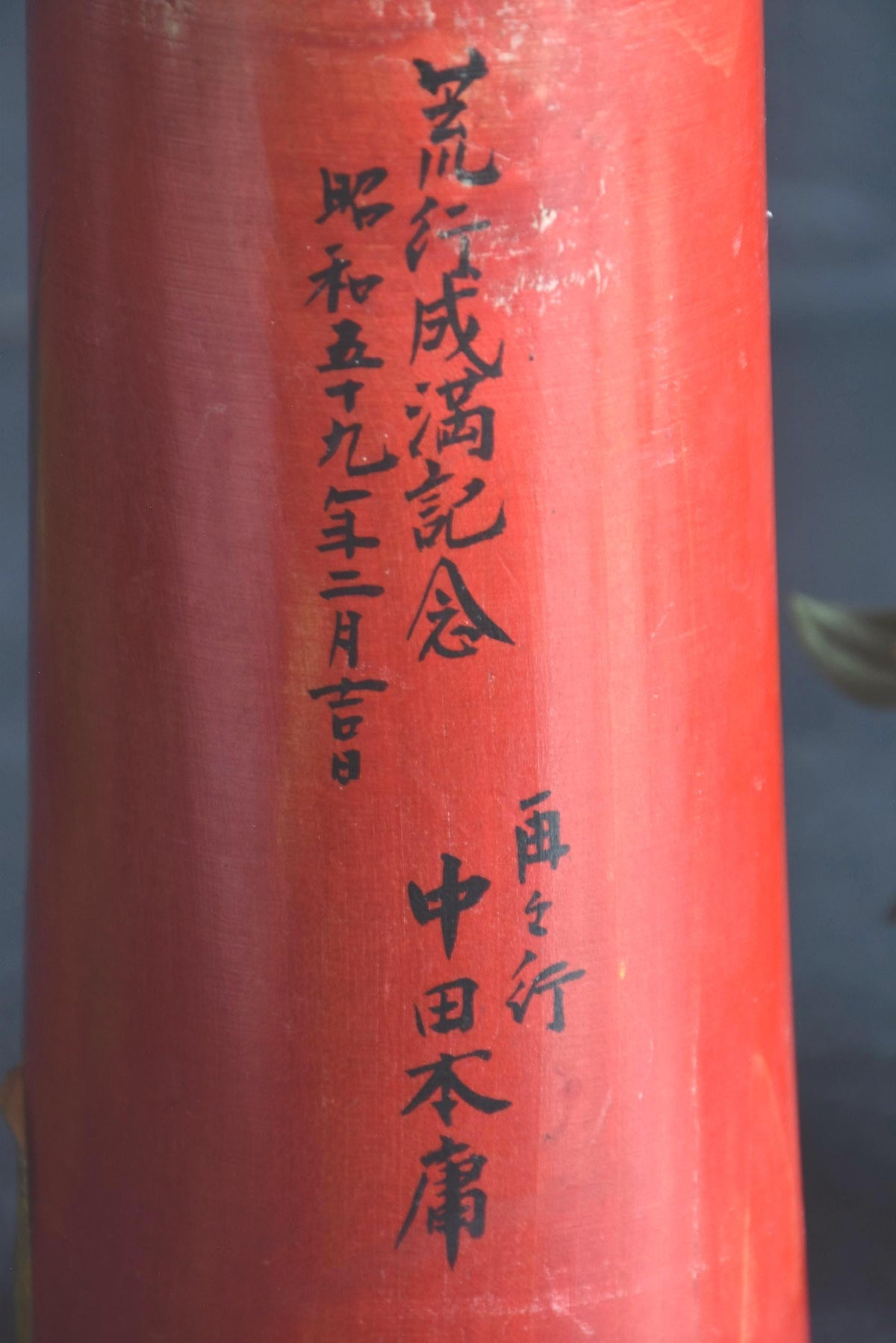 Hakuho Sosaku Kokeshi doll text detail showing close up of the vertical black Japanese calligraphy painted on the red body.