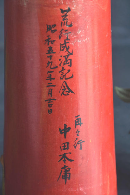Hakuho Sosaku Kokeshi doll text detail showing close up of the vertical black Japanese calligraphy painted on the red body.