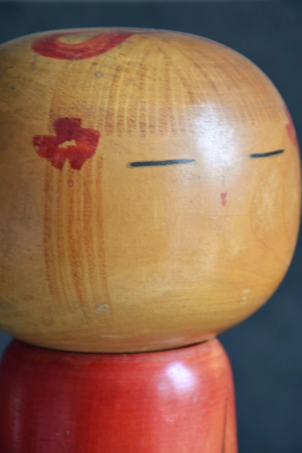 Hakuho Sosaku Kokeshi doll side profile view showing the painted floral hair ornament and wood grain on the head.