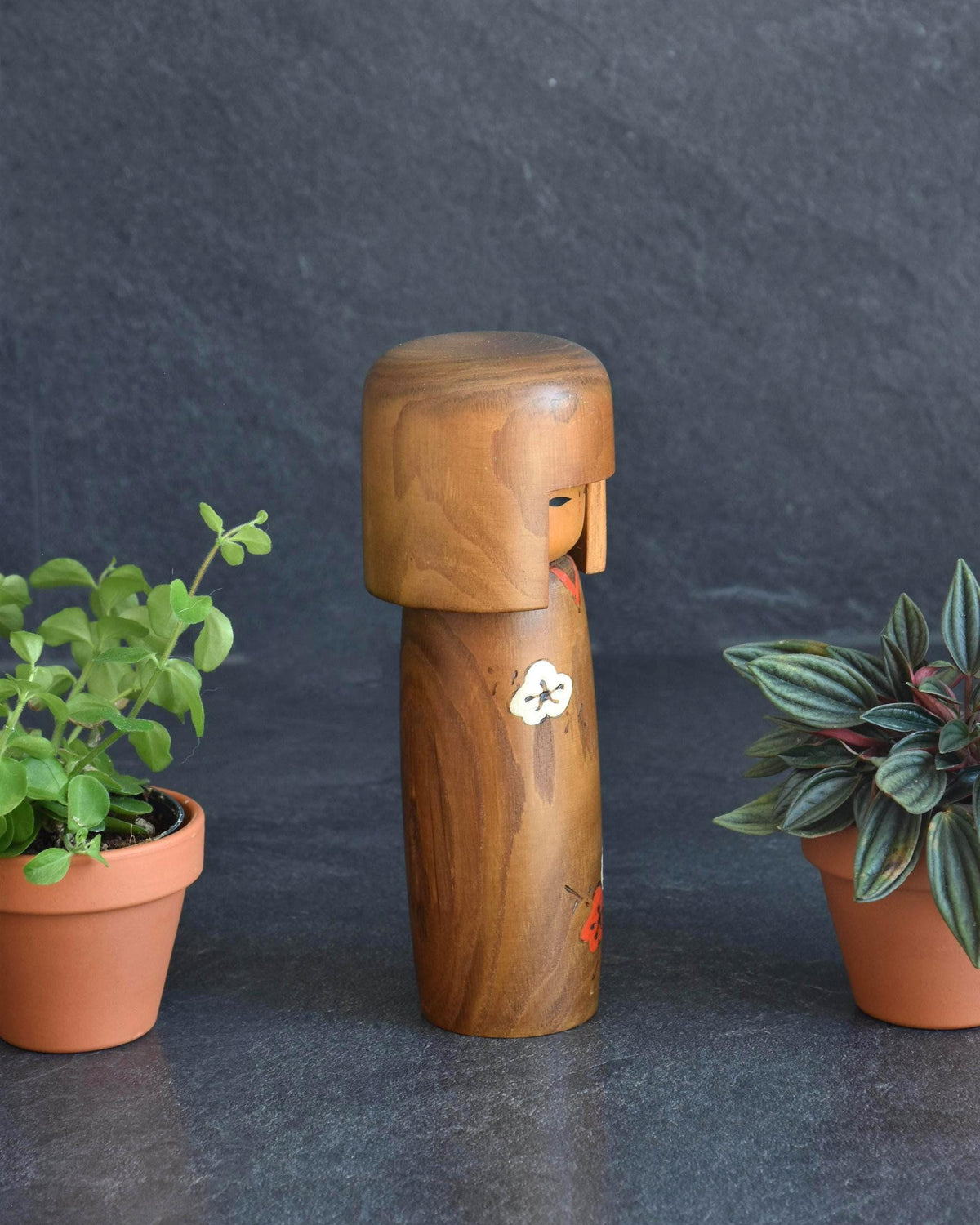 Usaburo kokeshi doll side view showing the left profile with plum blossom pattern