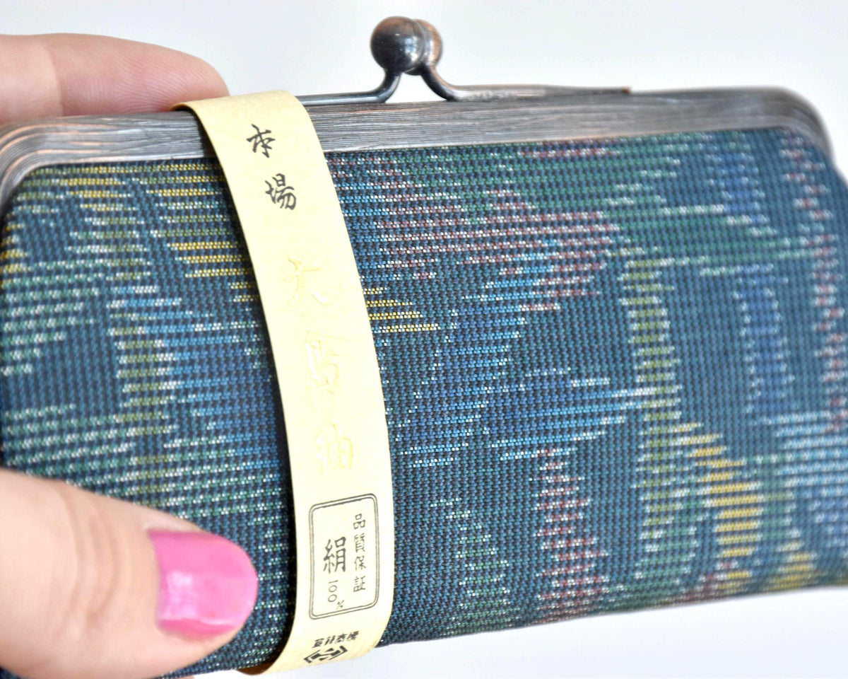 Blue Oshima Tsumugi Silk Gamaguchi Coin Purse close-up of the paper label wrapped around the silk body.
