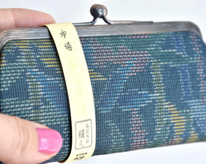 Blue Oshima Tsumugi Silk Gamaguchi Coin Purse close-up of the paper label wrapped around the silk body.